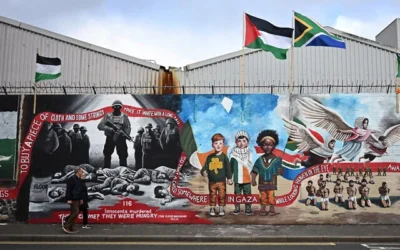 Des passants se promènent devant une fresque murale représentant des soldats israéliens ténébreux sur le mur international de Falls Road à Belfast, en Irlande du Nord, le 19 mars 2024. (Crédit : Paul Ellis/AFP)