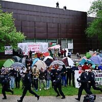 Illustration : Des policiers passent devant des militants pro-palestiniens et anti-israéliens sur le campus de l'Université libre de Berlin, en Allemagne, le 7 mai 2024. (Crédit : Tobias Schwarz/AFP)