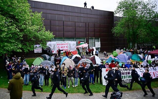 Illustration : Des policiers passent devant des militants pro-palestiniens et anti-israéliens sur le campus de l'Université libre de Berlin, en Allemagne, le 7 mai 2024. (Crédit : Tobias Schwarz/AFP)