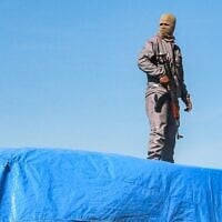 Un membre des forces de sécurité loyales au Hamas montant la garde sur l'un des camions transportant de l'aide humanitaire en provenance du poste-frontière de Kerem Shalom, à al-Shoka, à l'est de Rafah, dans le sud de la bande de Gaza, le 21 janvier 2025. (Crédit : Bashar Taleb/AFP)