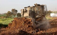 Un bulldozer D9 sans pilote creusant un champ lors d'une démonstration à la presse, dans les locaux d'Israel Aerospace Industries (IAI), près de Tel Aviv, le 26 mars 2025. (Crédit : Gil Cohen-Magen/AFP)