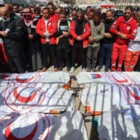 Des membres du Croissant-Rouge palestinien et d'autres services d'urgence priant près des corps de leurs collègues sauveteurs tués une semaine plus tôt par l'armée israélienne, lors d'un cortège funèbre à l'hôpital Nasser de Khan Younès, dans le sud de la bande de Gaza, le 31 mars 2025. (Crédit : Eyad Baba/AFP)