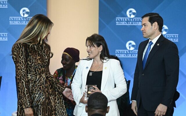 Amit Soussana (au centre), avocate et ex-otage israélienne rescapée du pogrom du 7 octobre 2023 perpétré par le Hamas, honorée par le secrétaire d'État américain, Marco Rubio (à droite), et la Première dame, Melania Trump (à gauche), lors de la cérémonie de remise du prix international des femmes de courage, au Département d'État, à Washington, le 1ᵉʳ avril 2025. (Crédit : Brendan Smialowski/AFP) Amit Soussana (au centre), avocate et ex-otage israélienne rescapée du pogrom du 7 octobre 2023 perpétré par le Hamas, honorée par le secrétaire d'État américain, Marco Rubio (à droite), et la Première dame, Melania Trump (à gauche), lors de la cérémonie de remise du prix international des femmes de courage, au Département d'État, à Washington, le 1ᵉʳ avril 2025. (Crédit : Brendan Smialowski/AFP)