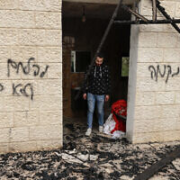 Un Palestinien passant devant des graffitis en hébreu : « Vengeance » (à droite), « Combattez l'ennemi, pas l'allié » (à gauche), dans un bâtiment après une attaque présumée de résidents d'implantations israéliens, dans la ville de Sadya à proximité de la ville de Salfit, en Cisjordanie, le 8 avril 2025. (Crédit : Jaafar Ashtiyeh/AFP)