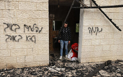 Un Palestinien passant devant des graffitis en hébreu : « Vengeance » (à droite), « Combattez l'ennemi, pas l'allié » (à gauche), dans un bâtiment après une attaque présumée de résidents d'implantations israéliens, dans la ville de Sadya à proximité de la ville de Salfit, en Cisjordanie, le 8 avril 2025. (Crédit : Jaafar Ashtiyeh/AFP)