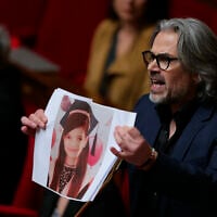 Aymeric Caron, député LFI, tient le portrait d'un enfant qui, selon lui, a été tuéé lors de l'offensive militaire israélienne à Gaza, alors qu'il prononce un discours lors de la séance des questions au gouvernement à l'Assemblée nationale, la chambre basse du Parlement français, à Paris, le 8 avril 2025. (Crédit : Thomas SAMSON / AFP)