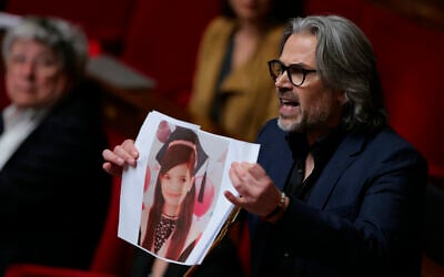 Aymeric Caron, député LFI, tient le portrait d'un enfant qui, selon lui, a été tué lors de l'offensive militaire israélienne à Gaza, alors qu'il prononce un discours lors de la séance des questions au gouvernement à l'Assemblée nationale, la chambre basse du Parlement français, à Paris, le 8 avril 2025. (Crédit : Thomas SAMSON / AFP)