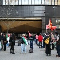 Des personnes se rassemblent devant l'Institut d'études politiques (Sciences-Po) de Strasbourg, certaines enveloppées dans un drapeau palestinien, alors que l'université doit voter sur le maintien ou non de son partenariat avec l'université Reichman à Herzliya, en Israël, le 8 avril 2025. (Crédit : Frederick FLORIN / AFP)