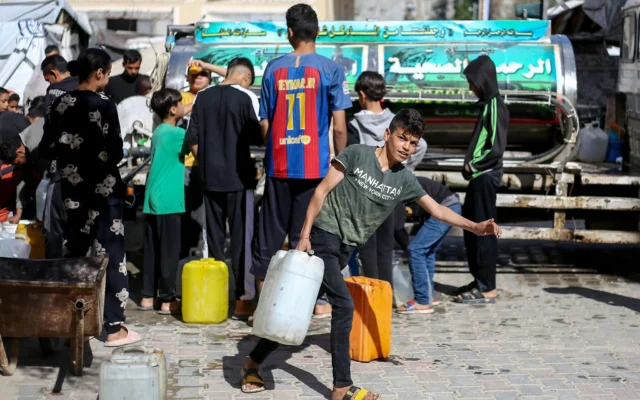 Des Palestiniens déplacés font la queue pour remplir leurs conteneurs d'eau au camp de réfugiés de Bureij, dans le centre de la bande de Gaza, le 10 avril 2025. (Crédit : Eyad BABA / AFP) Des Palestiniens déplacés font la queue pour remplir leurs conteneurs d'eau au camp de réfugiés de Bureij, dans le centre de la bande de Gaza, le 10 avril 2025. (Crédit : Eyad BABA / AFP)