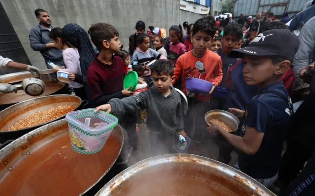 Des enfants palestiniens reçoivent leur part d'un repas chaud dans un point de distribution de nourriture gratuite dans le camp de réfugiés de Nuseirat, dans le centre de la bande de Gaza, le 12 avril 2025. (Crédit : Eyad BABA / AFP)