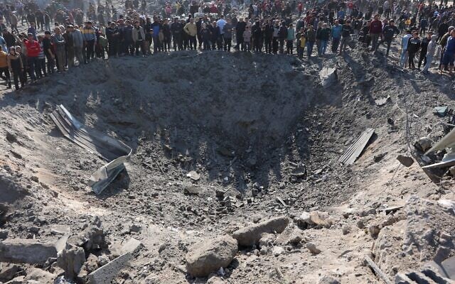 Des Palestiniens réunis autour d'un grand cratère suite à une frappe israélienne dans le quartier de Zaytoun, à Gaza, le 13 avril 2025. (Crédit : Omar Al-Qattaa/AFP) Des Palestiniens réunis autour d'un grand cratère suite à une frappe israélienne dans le quartier de Zaytoun, à Gaza, le 13 avril 2025. (Crédit : Omar Al-Qattaa/AFP)