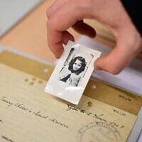 Une employée montrant la photo d'une jeune fille dans le cadre d'une recherche d'enfants dans un entrepôt de dossiers de victimes et de survivants du national-socialisme aux Archives d'Arolsen à Bad Arolsen, dans l'ouest de l'Allemagne, le 6 mars 2025. Les Archives d'Arolsen, qui font partie du programme Mémoire du monde de l'UNESCO, sont un centre international sur la persécution nazie qui a, selon ses propres déclarations, recueilli des informations sur environ 17,5 millions de personnes. Quatre-vingts ans après la fin de la Seconde Guerre mondiale, des personnes du monde entier découvrent encore le sort de leurs proches déportés dans des camps de la mort par le régime national-socialiste du dictateur allemand Adolf Hitler. (Crédit : Ina Fassbender/AFP)