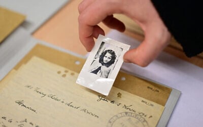 Une employée montrant la photo d'une jeune fille dans le cadre d'une recherche d'enfants dans un entrepôt de dossiers de victimes et de survivants du national-socialisme aux Archives d'Arolsen à Bad Arolsen, dans l'ouest de l'Allemagne, le 6 mars 2025. Les Archives d'Arolsen, qui font partie du programme Mémoire du monde de l'UNESCO, sont un centre international sur la persécution nazie qui a, selon ses propres déclarations, recueilli des informations sur environ 17,5 millions de personnes. Quatre-vingts ans après la fin de la Seconde Guerre mondiale, des personnes du monde entier découvrent encore le sort de leurs proches déportés dans des camps de la mort par le régime national-socialiste du dictateur allemand Adolf Hitler. (Crédit : Ina Fassbender/AFP)