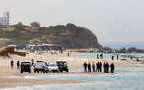 Illustration : Des membres de la police israélienne et des services de secours se rassemblent le long d'une plage lors des recherches d'un homme disparu dans les eaux de la Méditerranée au large de la côte de Hadera, dans le centre d'Israël, le 22 avril 2025. (Crédit : Jack Guez/AFP)