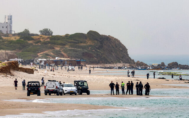 Des membres de la police israélienne et des services de secours se rassemblent le long d'une plage lors des recherches d'un homme disparu dans les eaux de la Méditerranée au large de la côte de Hadera, dans le centre d'Israël, le 22 avril 2025. (Crédit : JACK GUEZ / AFP)