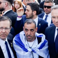 Le président Isaac Herzog (à gauche) pose avec l'ancien otage Eli Sharabi (au centre) et le président polonais Andrzej Duda (à droite) devant la porte « Arbeit macht frei » (Le travail vous rendra libre) du camp de concentration d'Auschwitz Birkenau à Oswiecim, en Pologne, le 24 avril 2025, avant la Marche des vivants (Wojtek Radwanski/AFP)