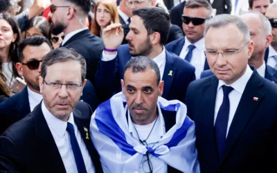 Le président Isaac Herzog (à gauche) pose avec l'ancien otage Eli Sharabi (au centre) et le président polonais Andrzej Duda (à droite) devant la porte « Arbeit macht frei » (Le travail vous rendra libre) du camp de concentration d'Auschwitz Birkenau à Oswiecim, en Pologne, le 24 avril 2025, avant la Marche des vivants (Wojtek Radwanski/AFP)