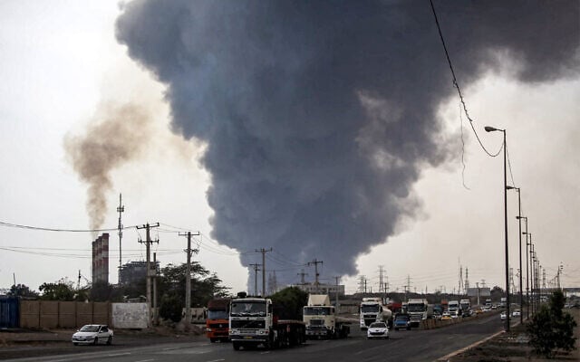 Un épais panache de fumée s’élevant alors que des automobilistes circulent sur une autoroute près du lieu d'une explosion au port Shahid Rajaee, au sud-ouest de Bandar Abbas, dans la province iranienne d'Hormozgan, le 26 avril 2025. Plusieurs conteneurs ont explosé le 26 avril dans le plus grand port commercial d'Iran, ont indiqué les autorités, provoquant une violente explosion et un incendie qui ont fait des centaines de blessés. Shahid Rajaee, situé à plus de 1 000 kilomètres au sud de la capitale, est le port à conteneurs le plus moderne d'Iran, selon l'agence de presse officielle IRNA. (Crédit : Mohammad Rasole Moradi/IRNA/AFP)