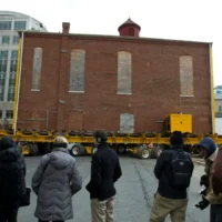 Illustration : Des badauds regardent des ouvriers déplacer la synagogue Adas Israel, la plus ancienne synagogue de Washington, vers un nouvel emplacement plus bas dans la rue, pour accueillir le Musée juif de la capitale, le 9 janvier 2019, à Washington, DC. (Crédit : AP Photo/Jose Luis Magana)
