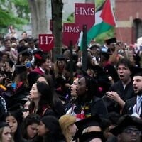 Des étudiants diplômés scandant des slogans alors qu'ils quittent la cérémonie de remise des diplômes en signe de protestation pour les treize diplômés de dernière année qui n'ont pas été autorisés à y participer en raison de leurs activités de protestation,  lors de la cérémonie de remise des diplômes de l'Université de Harvard, à Cambridge, dans le Massachusetts, le 23 mai 2024. (Crédit : Charles Krupa/AP)