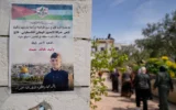 Des Palestiniennes passant devant une affiche représentant Walid Ahmad, sur laquelle on peut lire en arabe : "Le héros prisonnier martyr, la miséricorde et l'éternité pour nos justes martyrs", à Silwad, au nord-est de Ramallah, le 26 mars 2025. (Crédit : Nasser Nasser/AP)