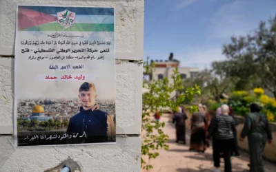 Des Palestiniennes passant devant une affiche représentant Walid Ahmad, sur laquelle on peut lire en arabe : "Le héros prisonnier martyr, la miséricorde et l'éternité pour nos justes martyrs", à Silwad, au nord-est de Ramallah, le 26 mars 2025. (Crédit : Nasser Nasser/AP)