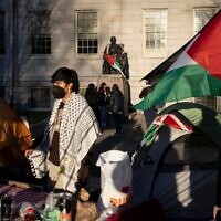 Un étudiant manifestant se tient devant la statue de John Harvard, le premier grand bienfaiteur de l'université de Harvard, drapée du drapeau palestinien, au milieu d'un campement d'étudiants protestant contre la guerre à Gaza, à l'université de Harvard à Cambridge, Massachusetts, le 25 avril 2024. (AP Photo/Ben Curtis, File)