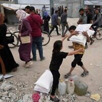 Des Palestiniens reçoivent des sacs de farine et d'autres éléments relevant de l'aide humanitaire distribués par l'UNRWA, l'agence de l'ONU qui aide les réfugiés palestiniens à Jabaliya, dans la bande de Gaza, le mardi 1er avril 2025. (Crédit : AP Photo/Jehad Alshrafi)