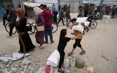 Des Palestiniens reçoivent des sacs de farine et d'autres éléments relevant de l'aide humanitaire distribués par l'UNRWA, l'agence de l'ONU qui aide les réfugiés palestiniens à Jabaliya, dans la bande de Gaza, le mardi 1er avril 2025. (Crédit : AP Photo/Jehad Alshrafi)