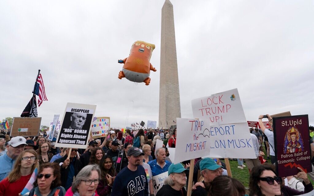 Des manifestants américains portant des pancartes lors des manifestations « Hands Off ! » contre le président américain Donald Trump et Elon Musk, au Washington Monument, le 5 avril 2025. (Crédit : Jose Luis Magana/AP)