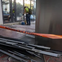 Un employé municipal nettoie la zone devant le siège de Hellenic Train, la principale compagnie ferroviaire grecque, après l'explosion d'une bombe le 11 avril 2025, causant des dégâts limités mais aucun blessé, à Athènes, le 12 avril 2025. (Crédit : AP Photo/Yorgos Karahalis)