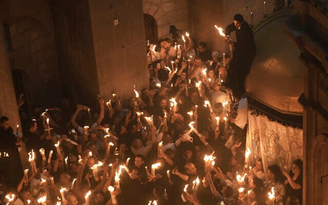 Les pèlerins chrétiens allument des bougies lors de la cérémonie du feu sacré dans l'église du Saint-Sépulcre, le site où, selon la tradition, Jésus a été crucifié et enterré, dans la Vieille ville de Jérusalem, le samedi 19 avril 2025. (Crédit : AP Photo/Mahmoud Illean)