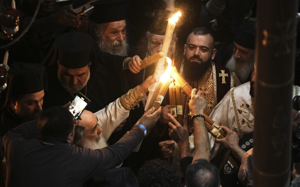 Le patriarche grec orthodoxe de Jérusalem Theophilos III, à gauche, allume des bougies pour les pèlerins chrétiens lors de la cérémonie du feu sacré, dans l'église du Saint-Sépulcre où, selon la tradition, Jésus a été crucifié et enterré, dans la Vieille ville de Jérusalem, le samedi 19 avril 2025. (Crédit : AP Photo/Mahmoud Illean)