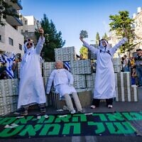 Des manifestants se moquant du Premier ministre Benjamin Netanyahu, qui était interrogé ce jour-là dans le cadre de l'enquête sur les liens de ses collaborateurs avec le Qatar, en allusion à sa politique menée depuis des années pour faciliter les paiements qataris au Hamas à Gaza, à Jérusalem, 31 mars 2025. (Crédit : Yonatan Sindel/Flash90)