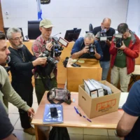 Des photographes prennent des photos d'une boîte de preuves présentée lors d'une audience au tribunal pour Jonatan Urich et Eli Feldstein qui ont été arrêtés dans le cadre de l'enquête sur le Qatargate, au tribunal de première instance de Rishon Lezion, le 1er avril 2025. (Crédit : Avshalom Sassoni/Flash90)