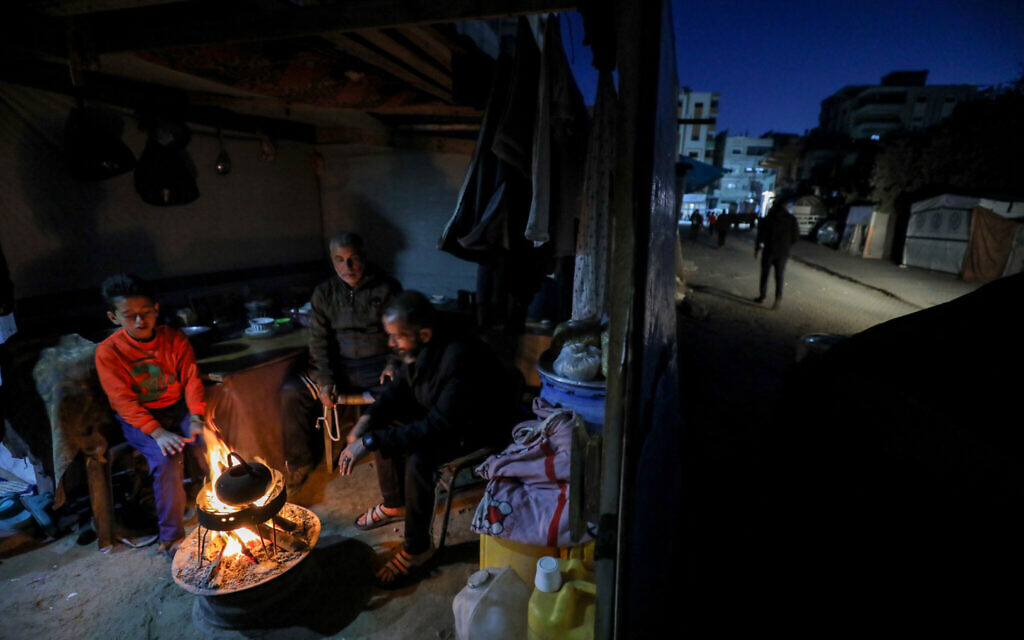 Des Palestiniens déplacés se réchauffent devant un feu de joie dans leur tente au centre de la bande de Gaza, le 16 avril 2025. (Crédit : Ali Hassan/Flash90)
חרבות ברזל
עזה
אוהלים
אוהל
מדורה