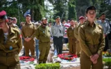 Les Israéliens restent immobiles alors qu'une sirène de deux minutes retentit dans tout Israël, marquant Yom HaZikaron, au cimetière militaire du Mont Herzl à Jérusalem, le 30 avril 2025. (Crédit : Arie Leib Abrams/Flash90)