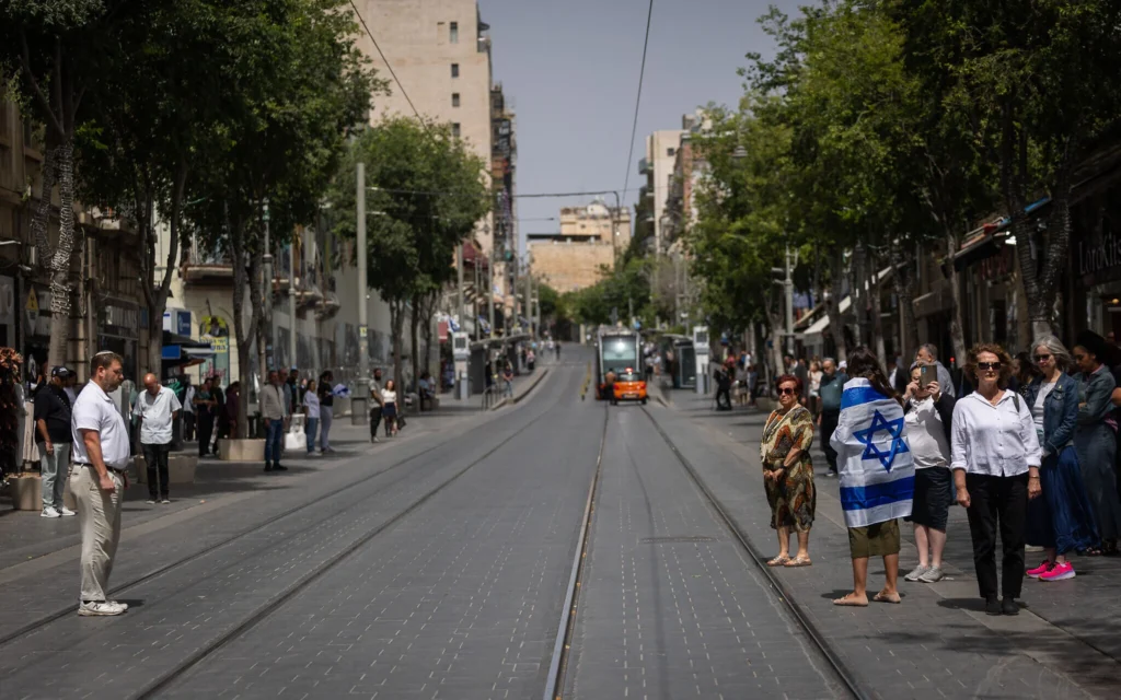 Les gens s'immobilisent alors qu'une sirène de deux minutes retentit dans tout Israël, à l'occasion de Yom HaZikaron qui commémore les soldats israéliens tombés au combat et les victimes de la terreur, à Jérusalem, le 30 avril 2025. (Crédit : Yonatan Sindel/Flash90)