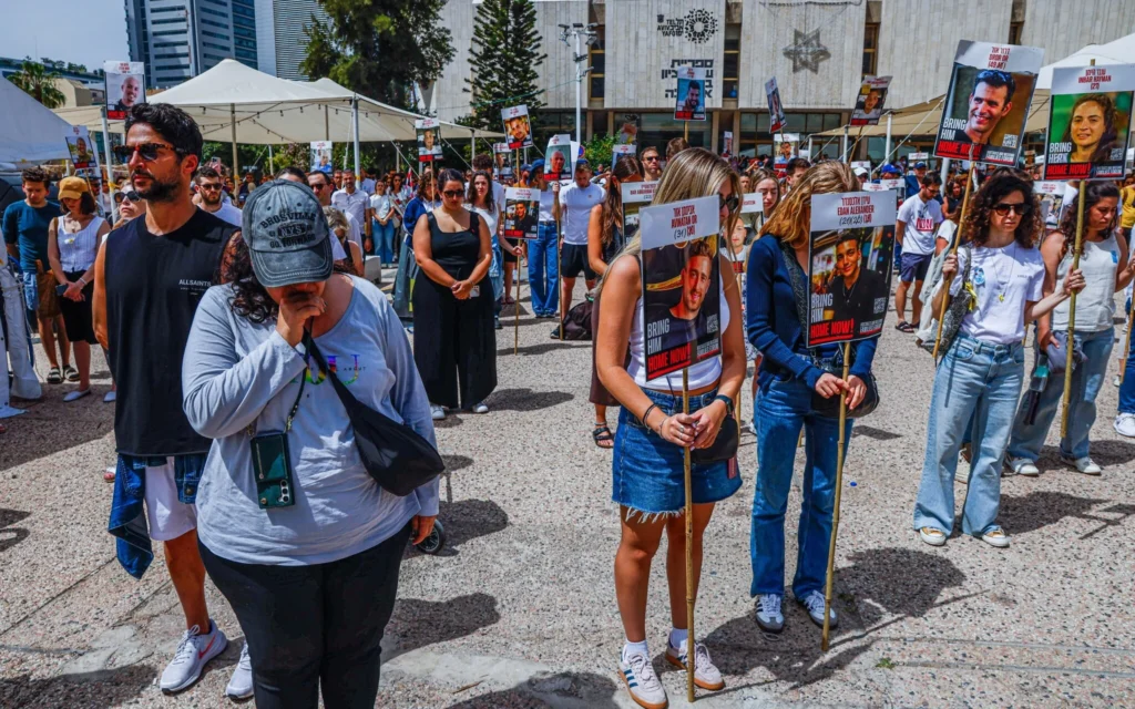 Des Israéliens s'immobilisent alors qu'une sirène retentit, à l'occasion de la Journée du souvenir, sur la place des Otages à Tel-Aviv, le 30 avril 2025. (Crédit : Yehoshua Yosef/Flash90)