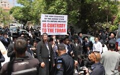 Des Juifs ultra-orthodoxes manifestent contre leur enrôlement dans l'armée devant un centre de recrutement de Tsahal à Jérusalem, en tenant notamment une pancarte sur laquelle est écrit en anglais « L'existence même de l'État sioniste et de son armée impure est contraire à la Torah », le 28 avril 2025. (Sam Sokol/Times of Israel)
