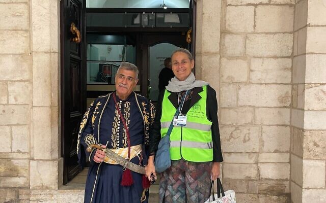 Yisca Harani se tient aux côtés d'un garde au Patriarcat latin de Jérusalem, dans la Vieille ville à l'occasion du Dimanche des Rameaux, le 13 avril 2025. ( Sue Surkes/Times of Israel)