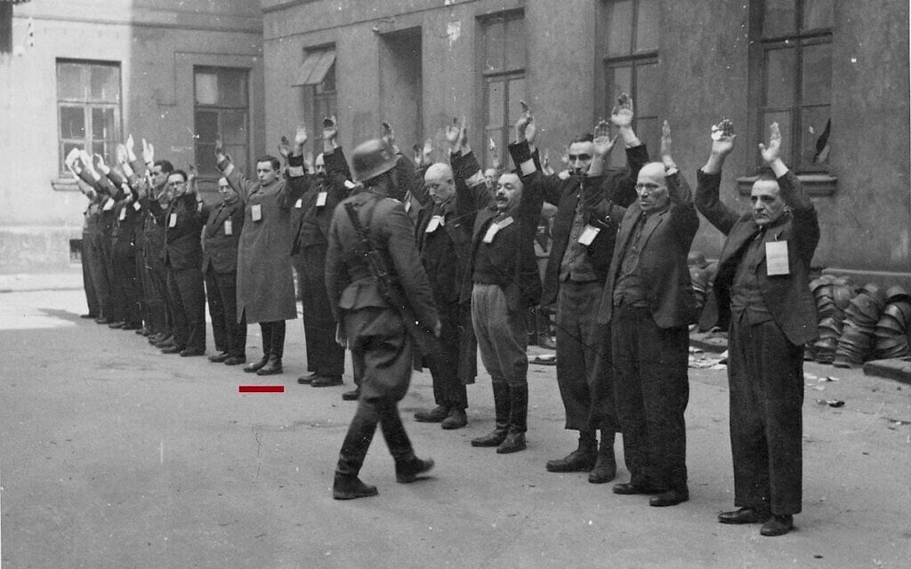 Les troupes allemandes arrêtant les derniers membres survivants du soulèvement du Ghetto de Varsovie, sur cette photo tirée du rapport Stroop. Un trait rouge marque l'emplacement de Michael Smuss, avec son père à sa droite. (Crédit : Collection des Archives nationales des États-Unis sur les crimes de guerre de la Seconde Guerre mondiale) Les troupes allemandes arrêtant les derniers membres survivants du soulèvement du Ghetto de Varsovie, sur cette photo tirée du rapport Stroop. Un trait rouge marque l'emplacement de Michael Smuss, avec son père à sa droite. (Crédit : Collection des Archives nationales des États-Unis sur les crimes de guerre de la Seconde Guerre mondiale)