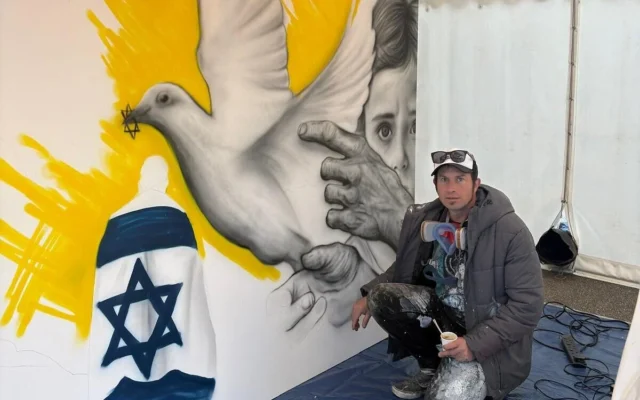 L'artiste israélien Benzi Brofman pose avec sa peinture murale « The Process » lors de la conférence sur l'antisémitisme contemporain qui s'est tenue du 29 mars au 1er avril 2025 dans le centre culturel juif JW3 de la ville. (Crédit : Lakruwan Rajapaksha)