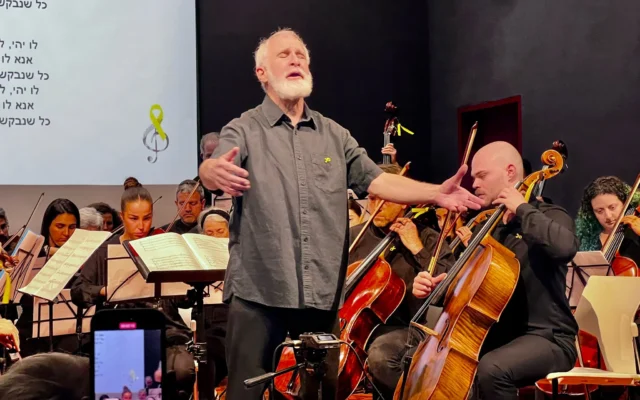 Le chef d'orchestre Michael Wolpe, avec l’ex-otage Agam Berger (derrière et à gauche), se produisant avec l'Orchestre Lu Yehi, à Jérusalem, le 8 avril 2025. (Crédit : Autorisation)