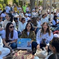 Anat Angrest (au centre) portant l'uniforme militaire de son fils Matan, aux côtés d'Idit Ohel, mère de l'otage Alon Ohel, lors d'un sit-in organisé par Mishmeret 101, à Kiryat Bialik, le 15 avril 2025. (Crédit : Shani Tamim/Mishmeret 101)