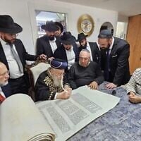 Le Grand Rabbin Yitzhak Yosef participe à l'écriture d'un rouleau de Torah dédié au sergent Segev Schwartz, 20 ans, tué au combat le 7 octobre 2023, avant Yom HaZikaron 2025. (Crédit : Ayelet HaShachar)