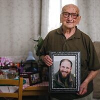 Asher Wolach tenant une photo commémorative du rabbin Avi Goldberg, en avril 2025. (Crédit : Gal Aharonovich/ International Fellowship of Christians and Jews)