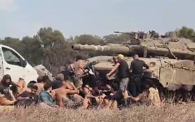 Des participants au festival Nova et des policiers cachés derrière un tank près du site du festival, le 7 octobre 2023. (Crédit : South First Responders) Des participants au festival Nova et des policiers cachés derrière un tank près du site du festival, le 7 octobre 2023. (Crédit : South First Responders)