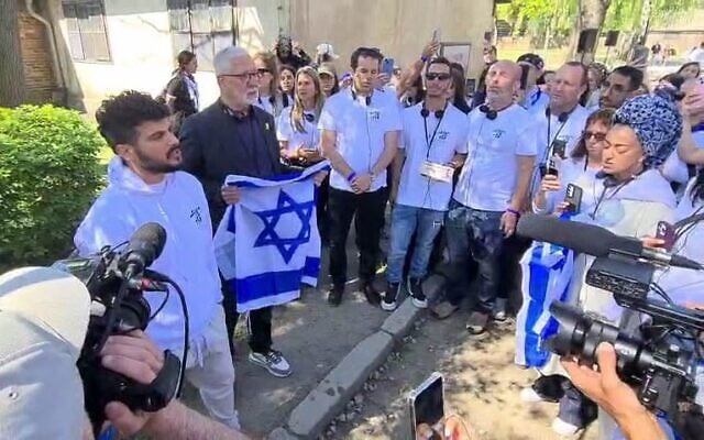 Daniel Weiss, survivant du kibboutz Beeri, chante avec des membres de sa famille sous le portail d'entrée d'Auschwitz, le 23 avril 2025. (Autorisation)