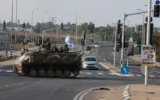 Illustration : Des soldats israéliens traversant une route principale dans un véhicule blindé de transport de troupes (APC), à la jonction de Shaar Hanegev près de Sderot, le 8 octobre 2023. (Crédit : Menahem Kahana/AFP)